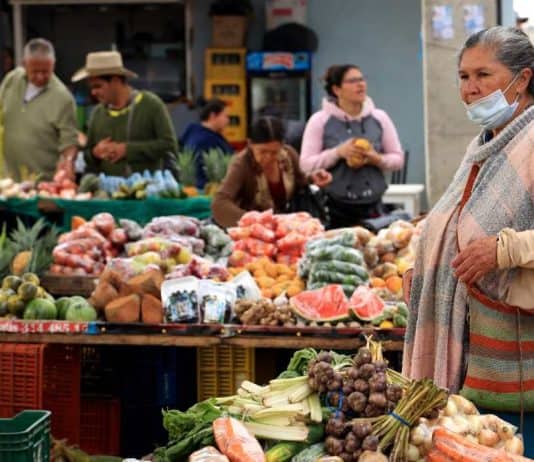 Mujer hace compras en una plaza de mercado de Colombia