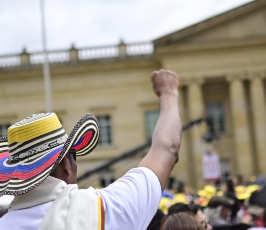 Un hombre levanta su mano en las marchas del 1 de mayo en Colombia, al frente de la Casa de Nariño