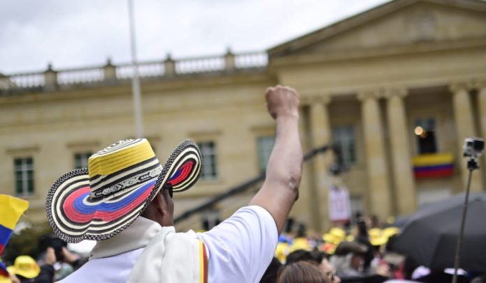 Un hombre levanta su mano en las marchas del 1 de mayo en Colombia, al frente de la Casa de Nariño